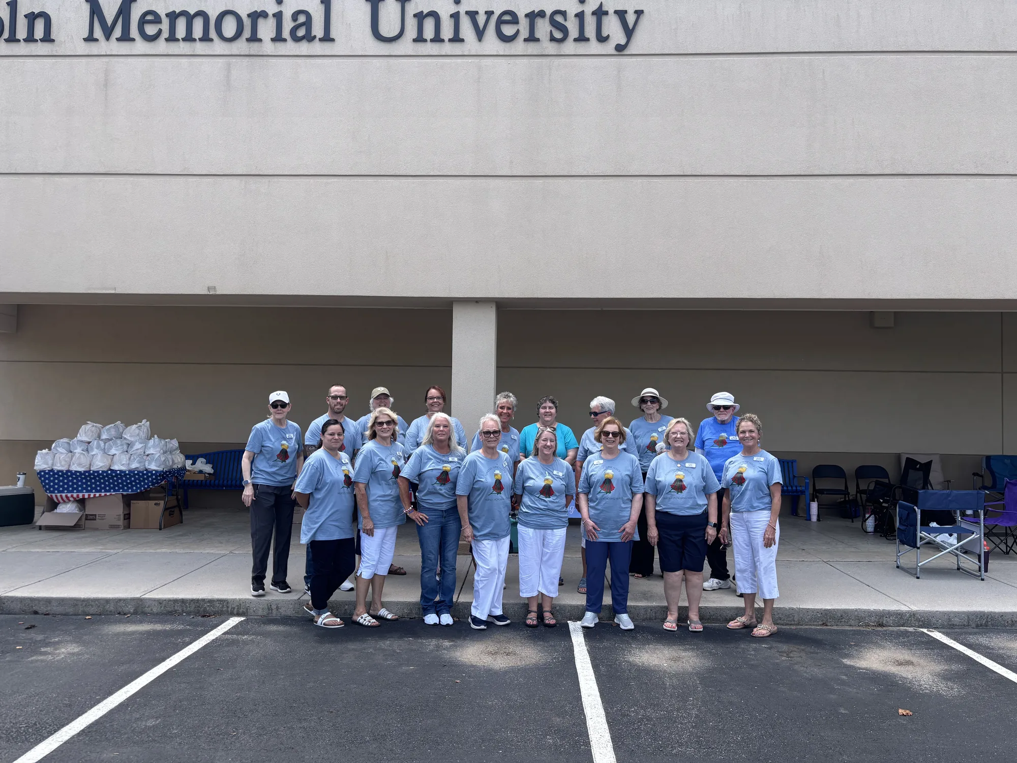 About twenty chapter volunteers in matching light blue t-shirts standing together outside Lincoln Memorial University on Butts for a Cause collection day, 2026.