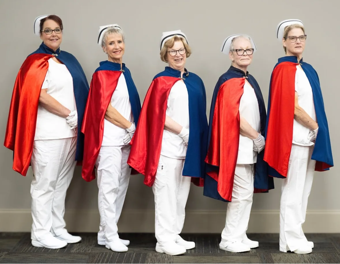 Five East Tennessee Nurse Honor Guard officers standing together in white uniforms with red and navy capes.