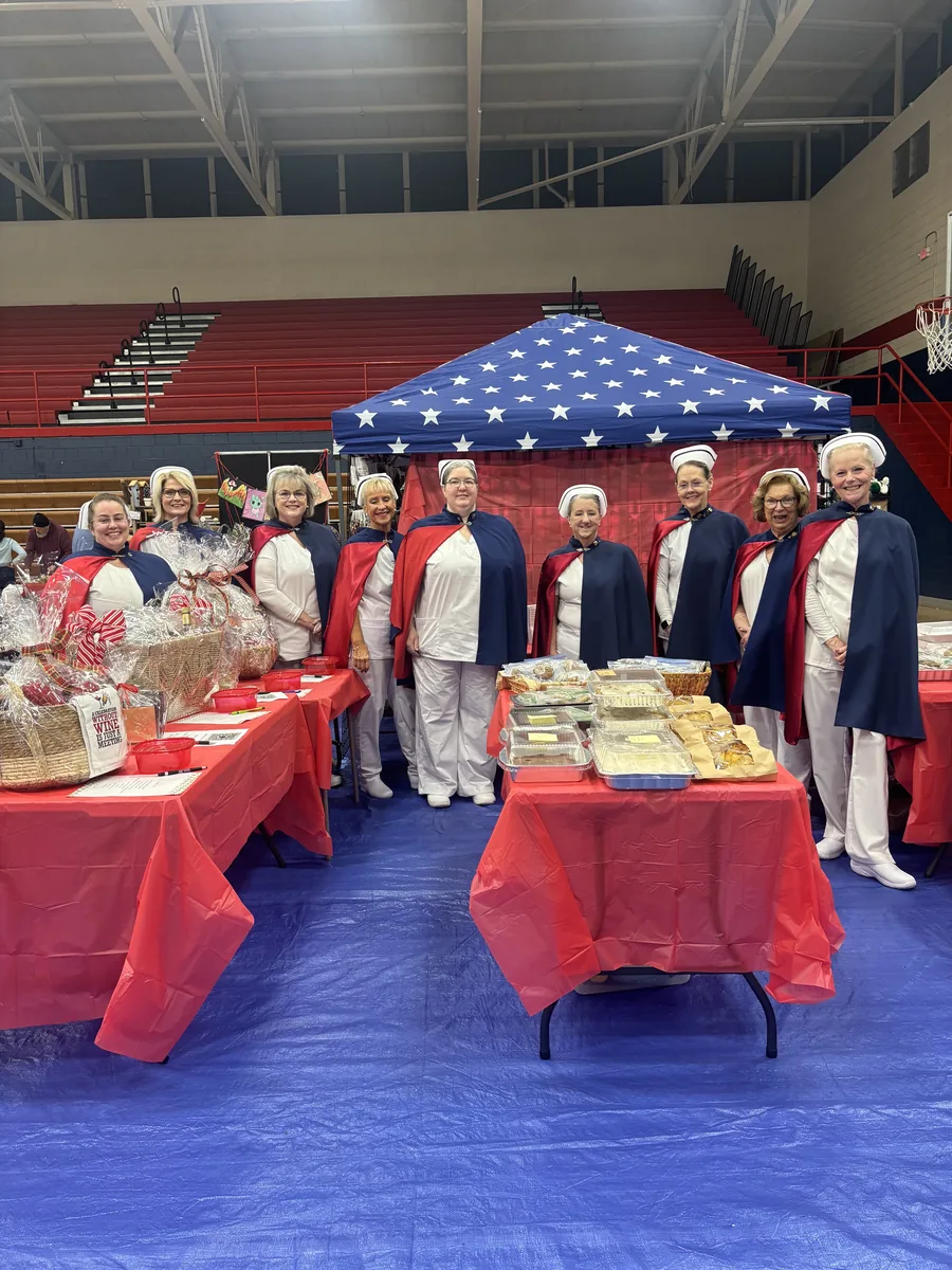 A fundraiser booth of baked goods set up beneath a stars and stripes canopy.