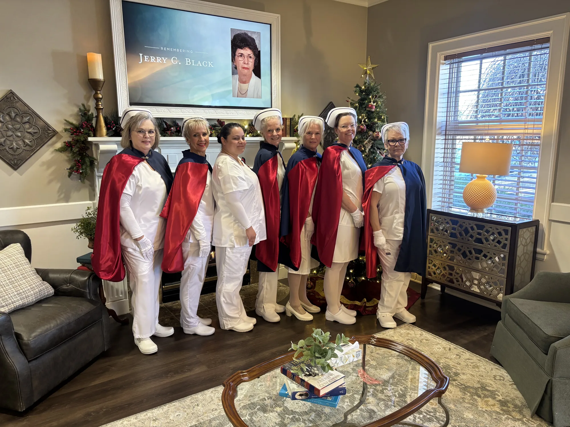 Honor guard members standing before a fireplace at a Final Tribute, beneath a memorial screen remembering Jerry C. Black, with a Christmas tree lit beside them.