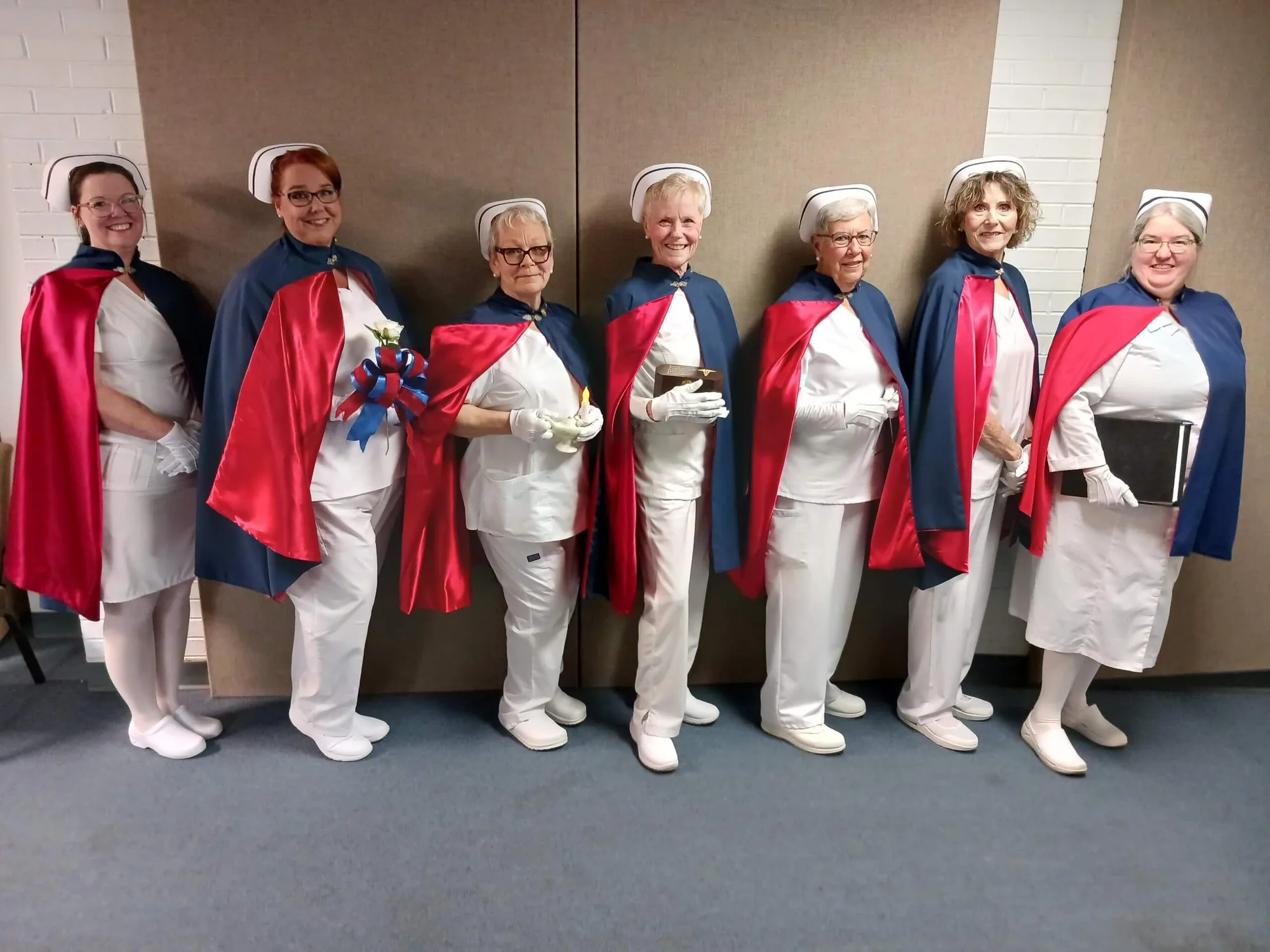 Seven honor guard members in formation, one holding the Nightingale lamp and one a book, at a service.