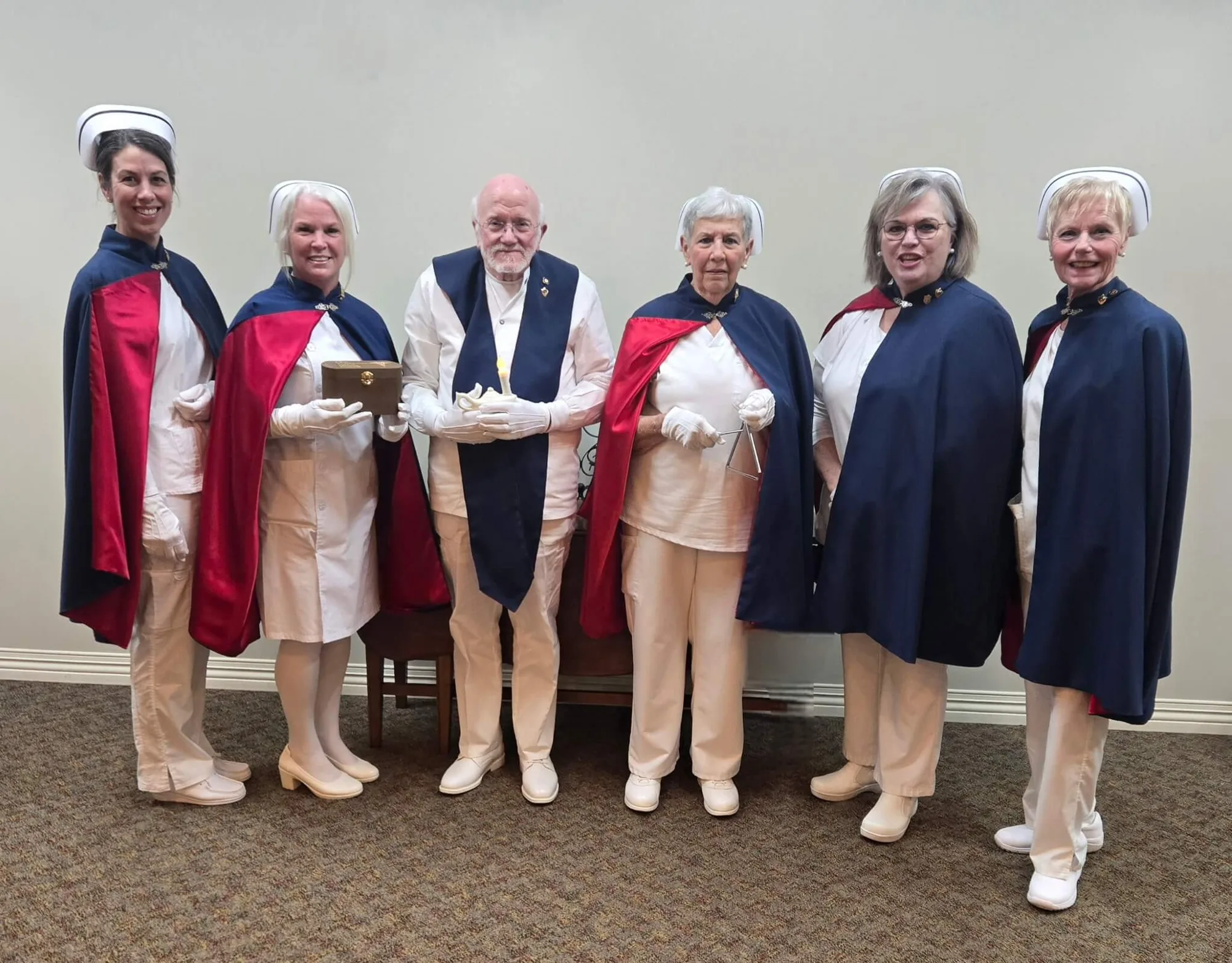 Six honor guard members standing together at a service, one of them holding the Nightingale lamp.
