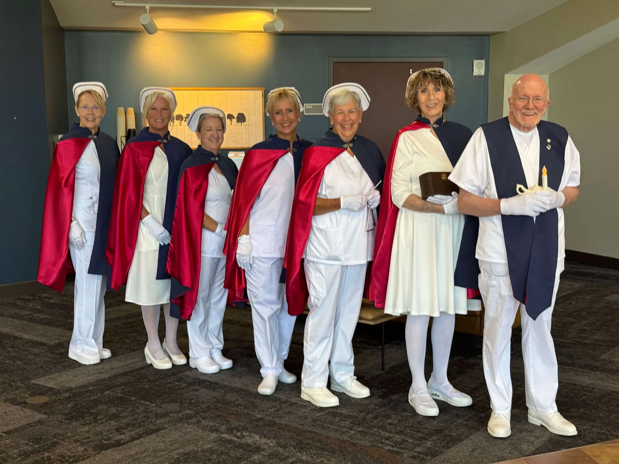Six honor guard members in formation, two of them carrying the Nightingale lamp and a lit candle, at a memorial service.