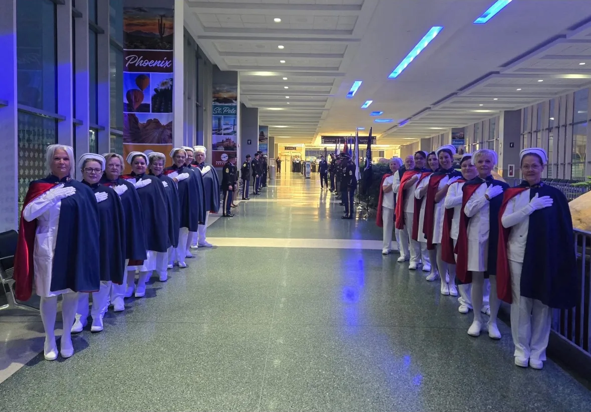 Honor guard members lined up along both sides of an airport concourse to form an honor cordon.
