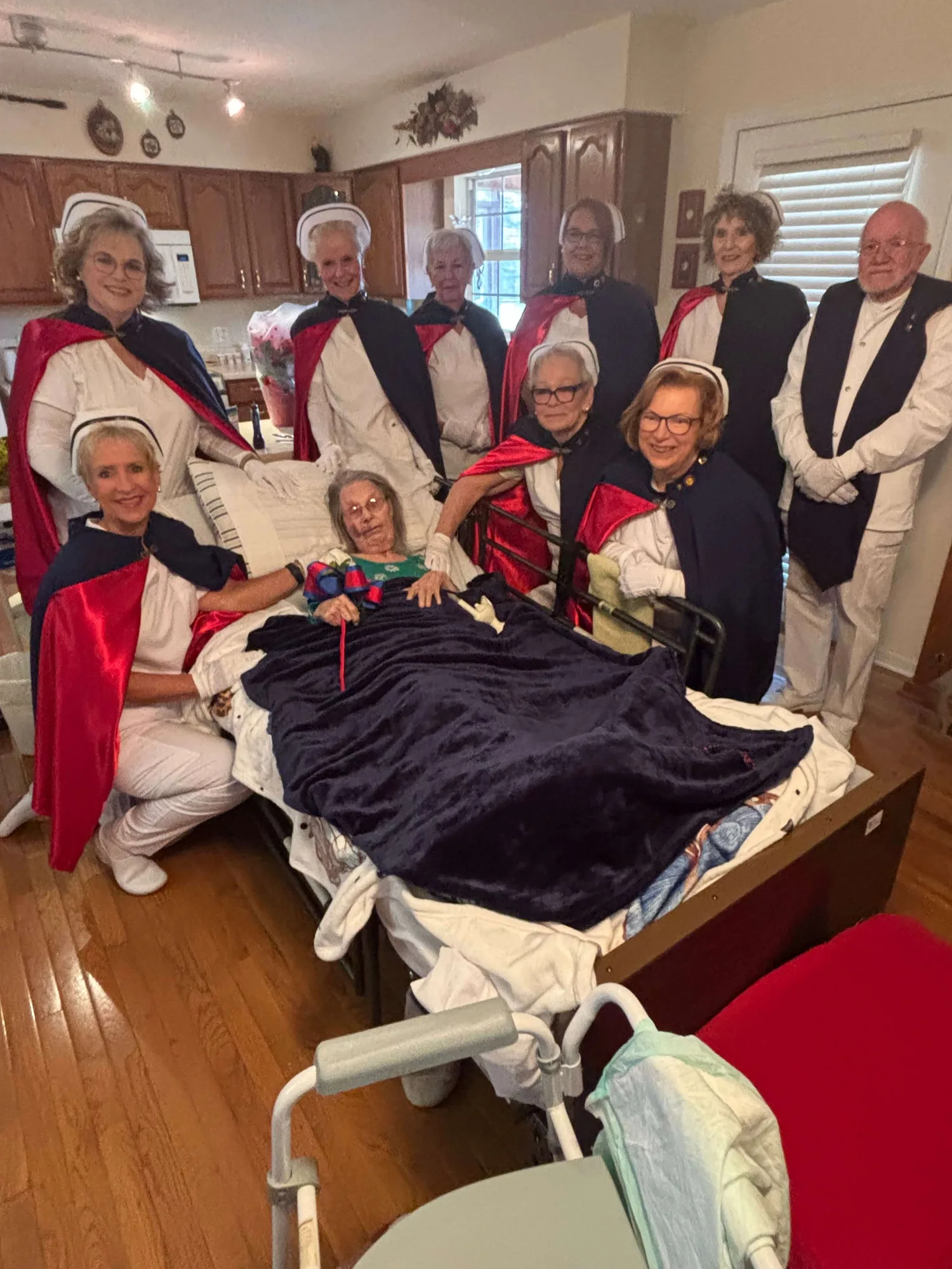 Honor guard members in white uniforms and capes gathered at the bedside of Carolyn Smith, RN, during her Living Tribute on 1 December 2025.