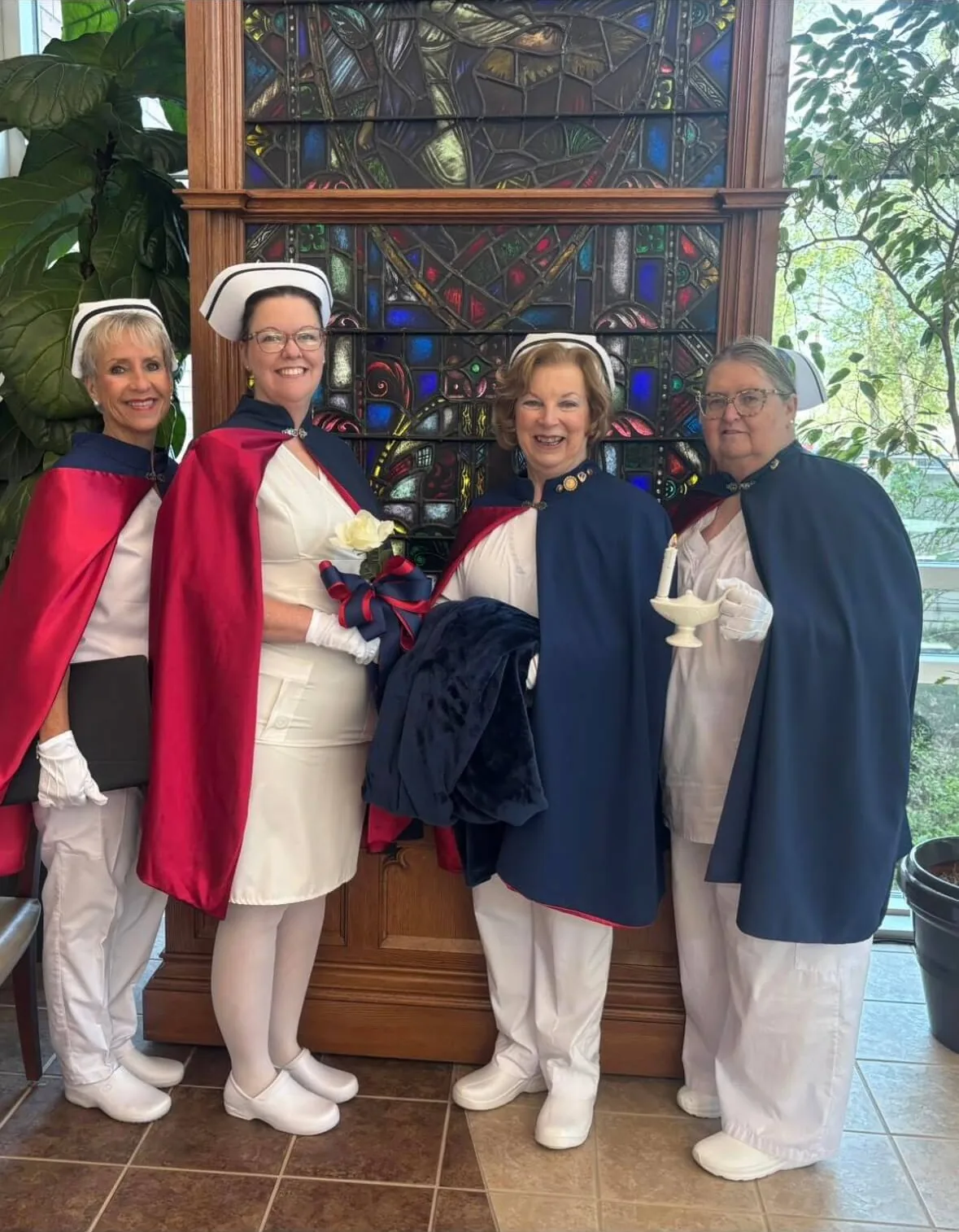 Four honor guard members in white uniforms and red and navy capes standing together at the Living Tribute for Mary Buttram, RN, on 6 April 2026.