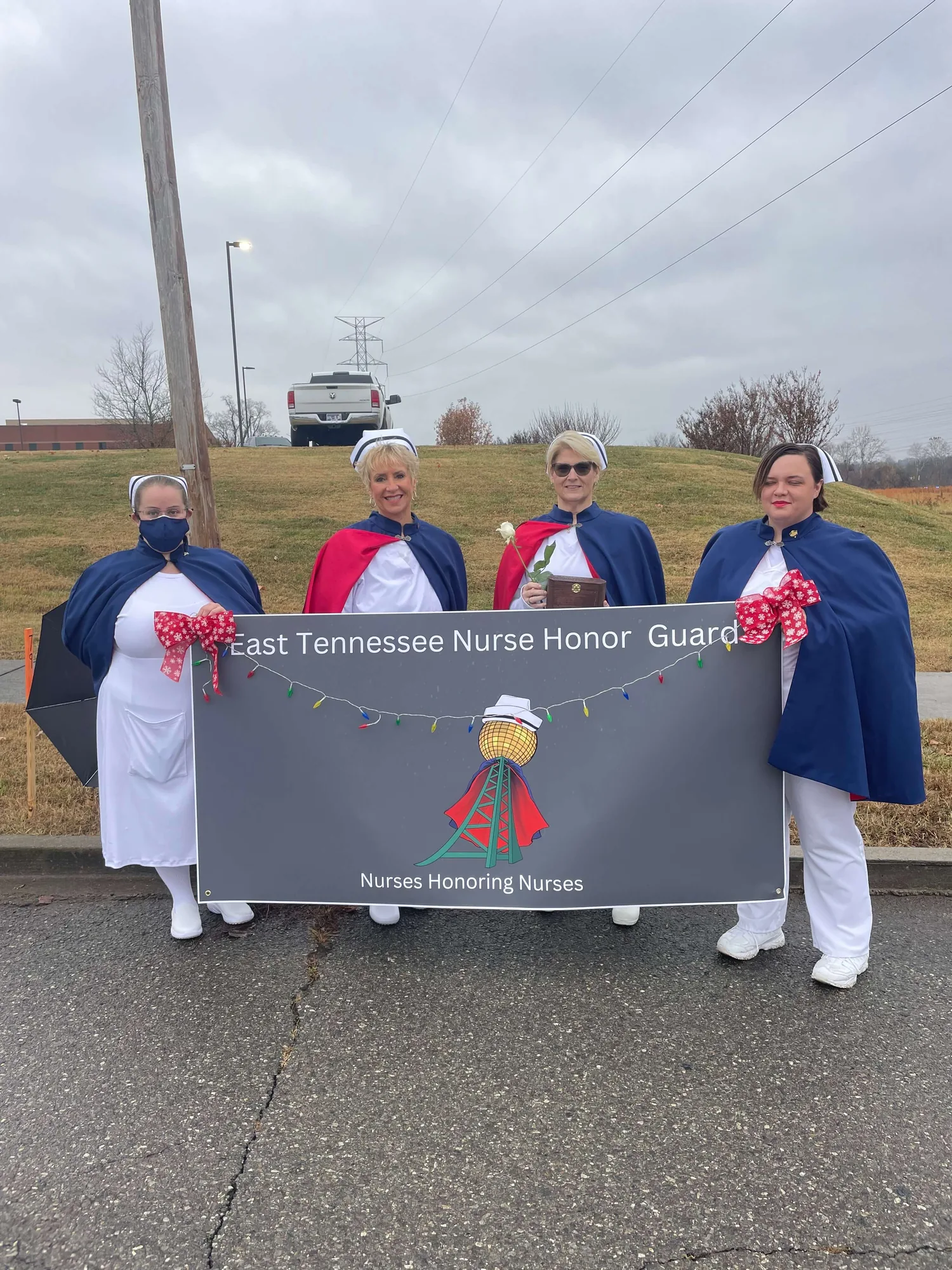Four honor guard members holding the chapter banner, decorated with red bows, at the 2024 Maryville Christmas parade.