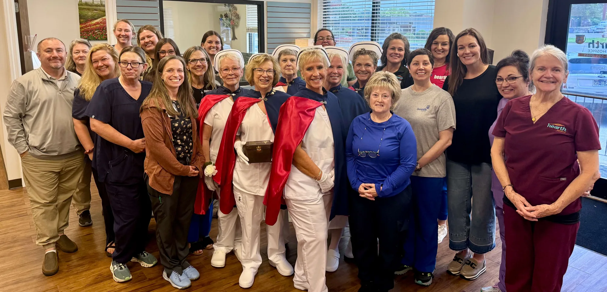 A large group of Hearth Hospice staff standing with two honor guard members in full uniform after a demonstration of the Final Tribute ceremony.