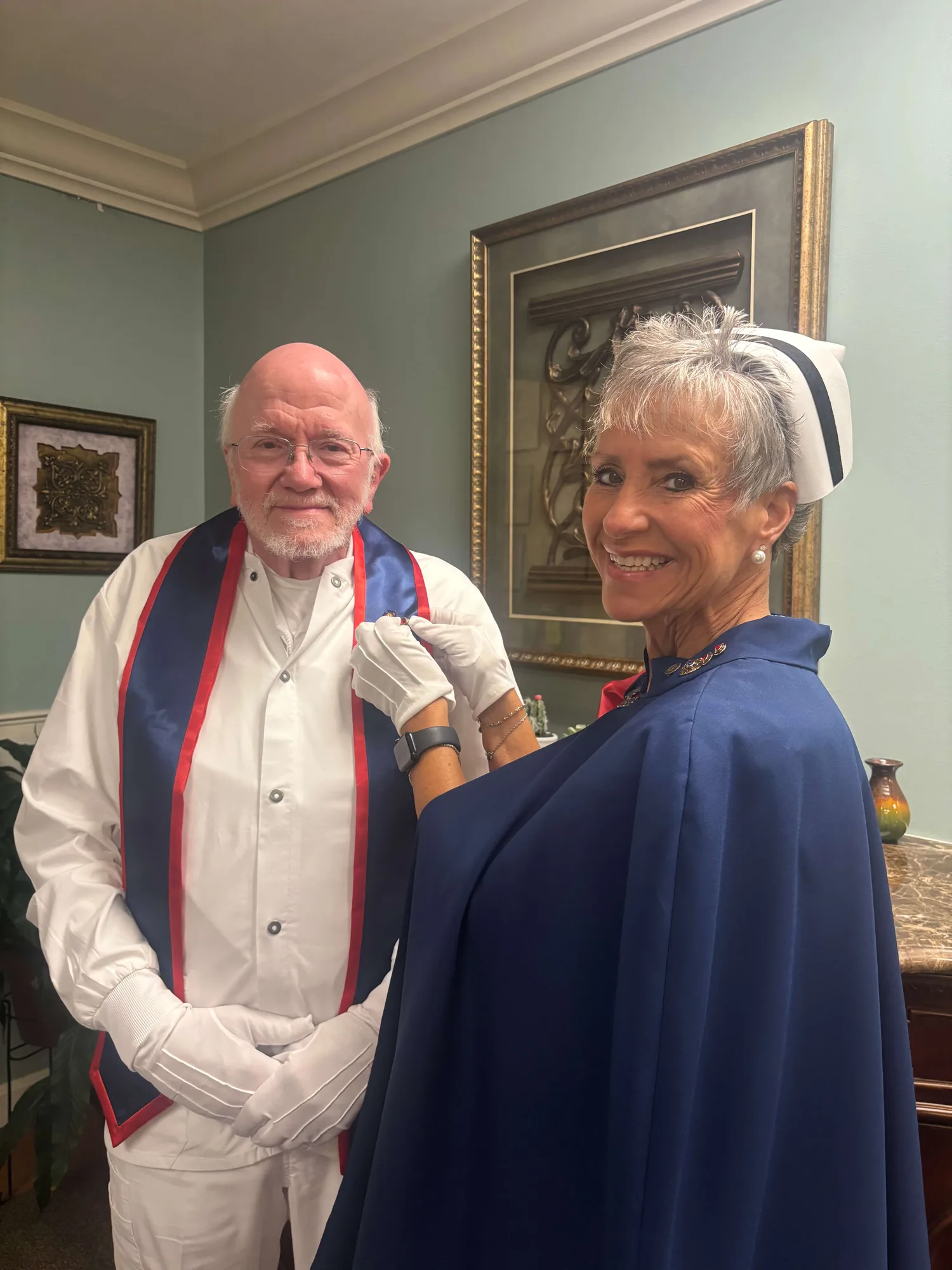 Bart McCuistion, in white uniform and cape, being pinned by Melanie Pfennigwerth for twenty-five services with the East Tennessee Nurse Honor Guard.