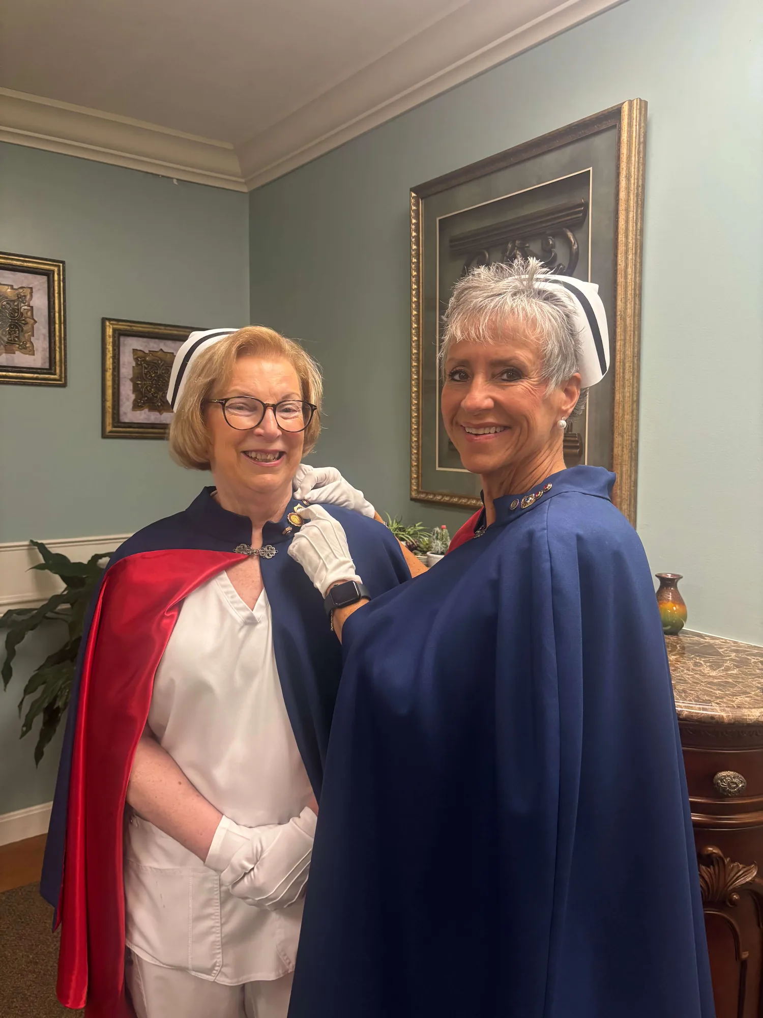 Jan Phillips, in white uniform and cape, being pinned by Melanie Pfennigwerth for twenty-five services with the East Tennessee Nurse Honor Guard.