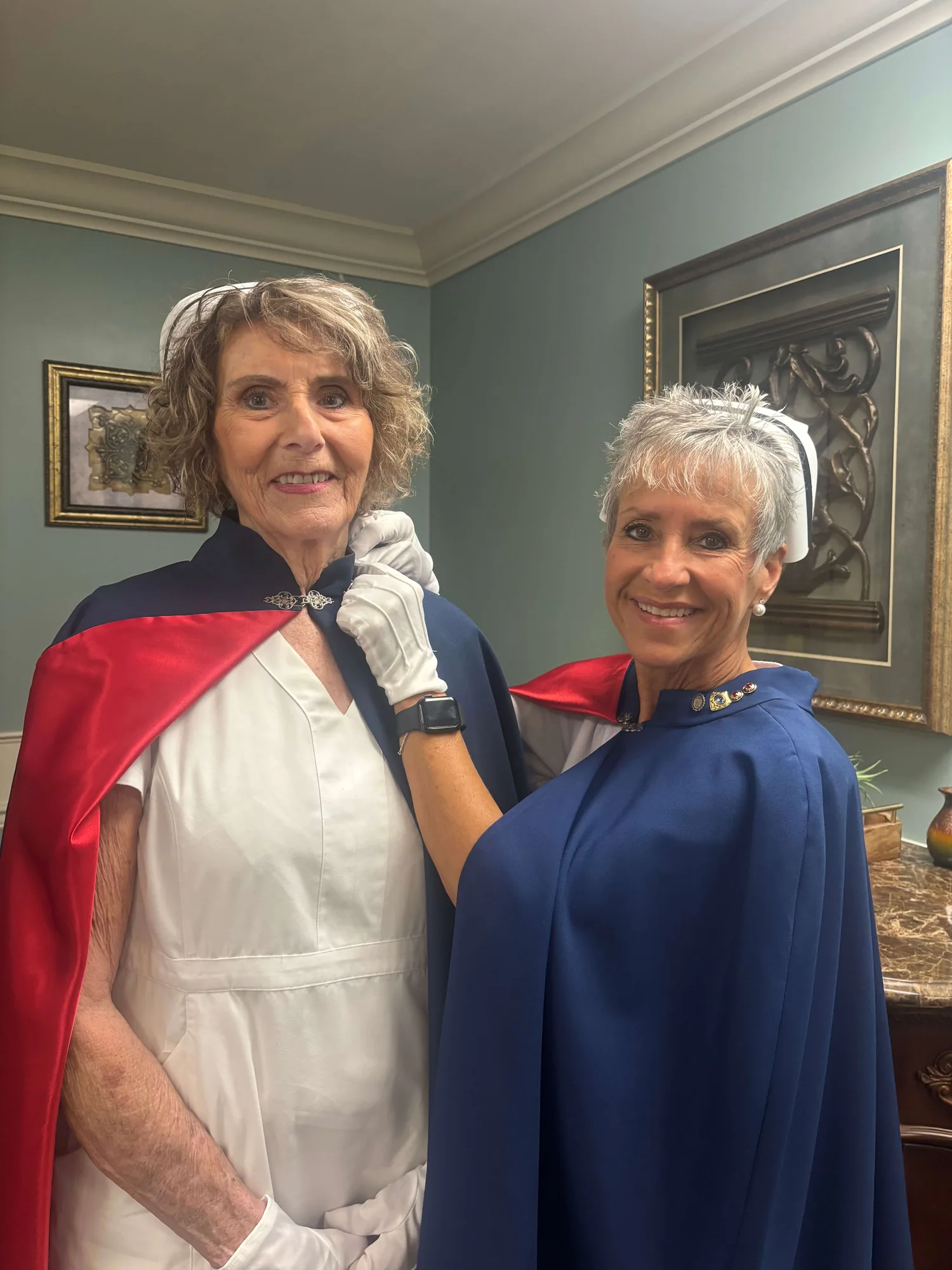 Vicky Lowe, in white uniform and cape, being pinned by Melanie Pfennigwerth for twenty-five services with the East Tennessee Nurse Honor Guard.