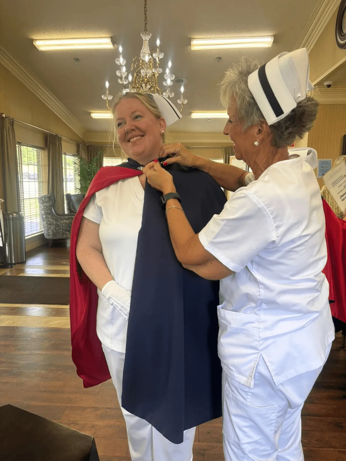Charlene Castleman, in white uniform and cape, being pinned by Melanie Pfennigwerth to mark a first service with the East Tennessee Nurse Honor Guard.