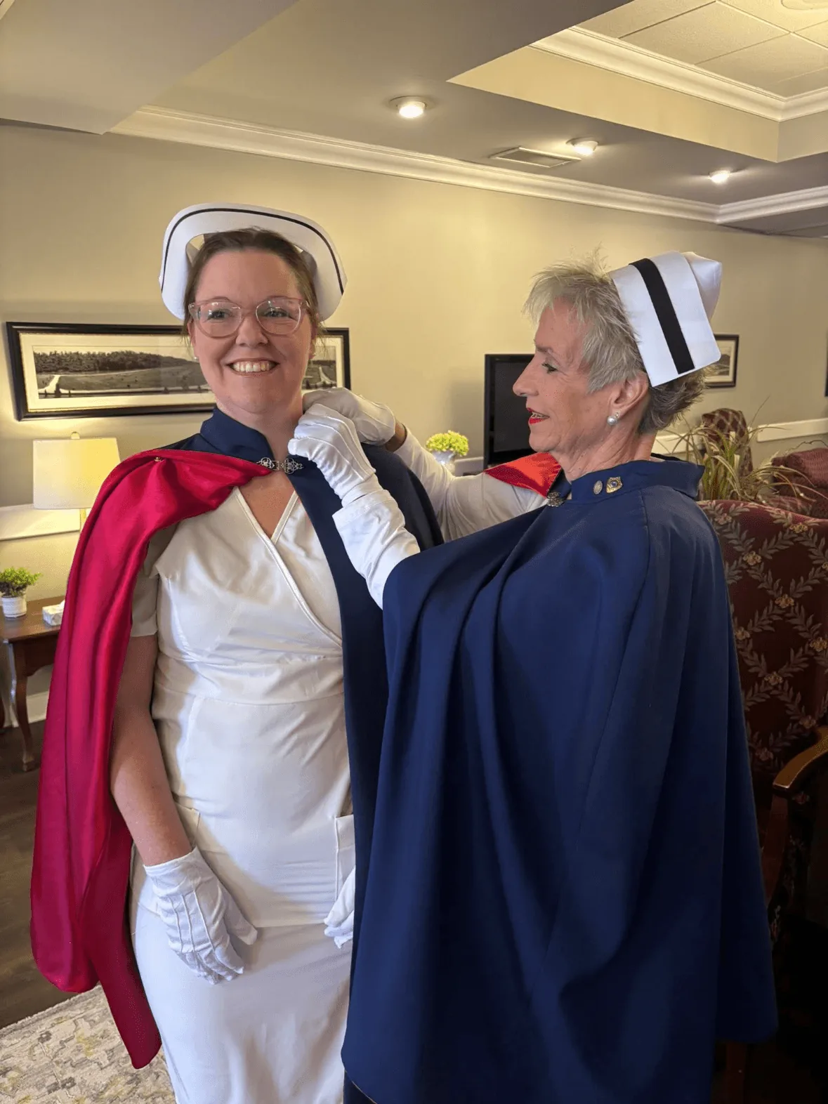 Christy Edmondson, in white uniform and cape, being pinned by Melanie Pfennigwerth to mark a first service with the East Tennessee Nurse Honor Guard.