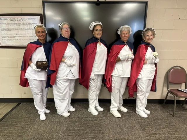 Five honor guard members standing in a classroom at the Tennessee College of Applied Technology, one holding an engraved East Tennessee Nurse Honor Guard plaque.