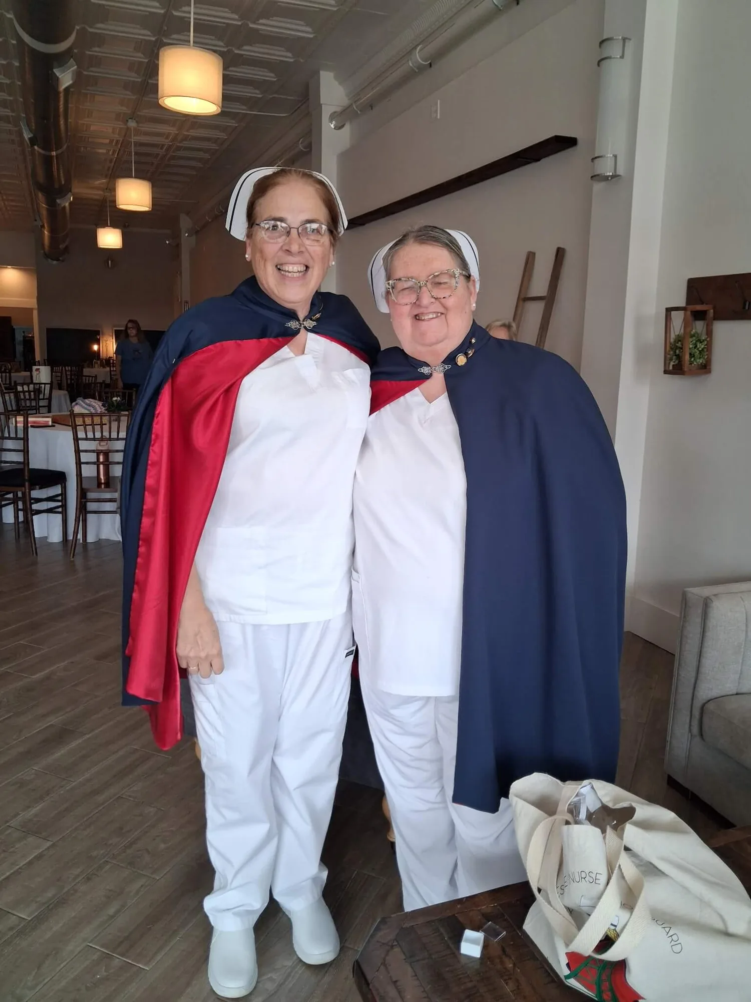 Two honor guard members in white uniforms and capes standing arm in arm indoors after a service.