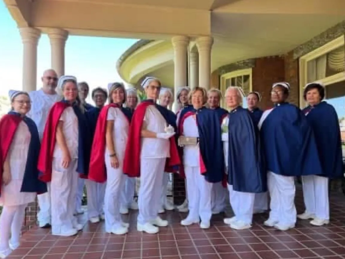 A large group of nurse honor guard members from several chapters gathered together on a covered porch.